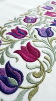 Colorful embroidered floral pattern with purple and pink tulips on white fabric showcasing traditional needlework craftsmanship for textile and fashion design.