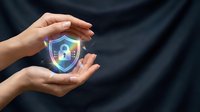 Hands holding glowing shield with padlock symbol against dark background, representing cybersecurity protection and data safety for digital security concepts.