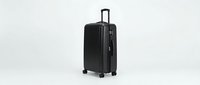 Modern black hardshell suitcase with four wheels and telescopic handle isolated on white background for travel and vacation concepts.