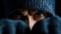Close up portrait of intense eyes under dark knit beanie hat, dramatic moody lighting creates mysterious atmosphere. Artistic cinematic composition.