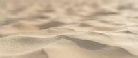 Close-up view of golden sand dunes with soft ripples and natural texture patterns created by wind, perfect for desert landscapes and nature backgrounds.