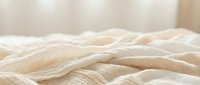 Crumpled beige linen fabric with soft folds and natural texture, suitable for home decor, bedding, and textile design projects.