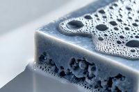 Handmade natural soap bar with activated charcoal and sea salt, organic skincare product with bubbles and foam texture for spa and wellness treatments.