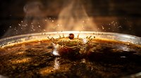 Liquid amber splash with crown formation and droplets suspended in motion, suitable for beverage, luxury, and abstract design projects.