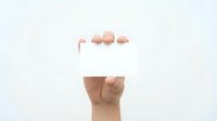 Hand holding blank white business card mockup against light background for branding and corporate identity design projects.