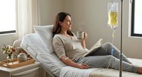 Young Caucasian woman patient relaxing in hospital bed with IV drip, holding coffee cup while reading book. Healthcare recovery and medical treatment concept.