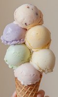 Stack of six colorful ice cream scoops in waffle cone with pastel flavors including vanilla, strawberry, pistachio and lavender on neutral background.