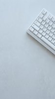 White wireless keyboard on light gray textured surface with copy space, suitable for technology, office, workspace, and digital design projects.