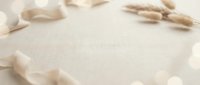 Soft beige fabric background with delicate rose petals scattered around edges creating romantic feminine frame with copy space for wedding invitations.