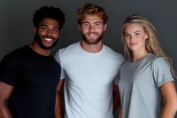 Three diverse young adults smiling together in casual wear against dark background. Mixed race man, Caucasian man with beard, blonde woman in friendship portrait.