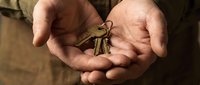 Hands holding house keys offering new home ownership opportunity for real estate investment property rental or mortgage lending services.