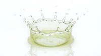Water crown splash with green tinted liquid creating dynamic droplets and ripples on white background for beverage and freshness concepts.