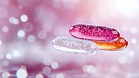 Colorful glazed donuts with sparkly sugar coating on pink bokeh background. Sweet dessert food photography with magical glittering effect and soft focus.
