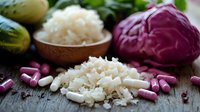 Fresh white rice in wooden bowl with purple cabbage and medical capsules on rustic wooden table, healthy eating and supplement concept.