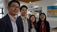 Happy Asian business team of four professionals smiling in modern office environment with casual and formal attire during workplace meeting.