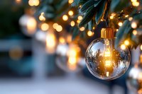 Clear glass Christmas ornament hanging from evergreen branch with warm golden bokeh lights creating festive holiday atmosphere for seasonal decorations.