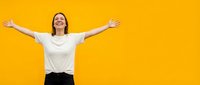 Woman with arms raised in celebration against yellow background, expressing joy and success for motivational and lifestyle content.