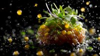 Fresh salmon tartare garnished with microgreens and flying caviar drops on dark background with water splashes and dramatic lighting creates gourmet atmosphere.