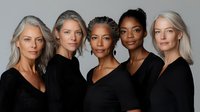 Diverse group of mature women wearing black sweaters pose confidently against neutral background, showcasing natural beauty, aging gracefully and female empowerment.