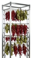 Red and green chili peppers hanging to dry on metal drying rack with multiple shelves for food preservation and storage.