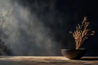 Minimalist ceramic bowl with dried golden grass stems on wooden surface against dark moody background with dramatic lighting and smoke effects.