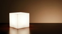 Glowing white cube lamp on dark wooden surface with warm brown background, modern minimalist lighting fixture for interior design and home decor.