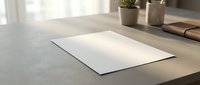 Blank white paper sheet on modern wooden desk with soft natural lighting for business presentations and creative projects.