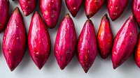 Fresh pink prickly pear fruits arranged in row on gray background, showing vibrant natural pattern of exotic cactus figs with water drops on surface.