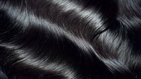 Luxurious black wavy hair with glossy shine and smooth texture, closeup of healthy hair strands showing natural movement for beauty and haircare industry.