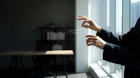 Professional businesswoman hands gesturing during presentation or meeting in modern office space with natural window lighting and contemporary furniture.