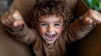 Joyful young child with curly hair and bright blue eyes expressing pure happiness and excitement while wearing brown clothing. Natural candid moment.