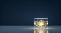 Glowing string lights inside transparent cube on dark blue background, creating warm ambient lighting effect for interior design and decoration projects.