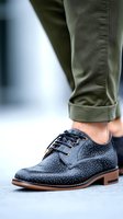 Stylish polka dot leather oxford shoe with olive green rolled pants leg, showcasing contemporary men's fashion detail on blurred background.