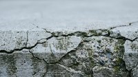 Cracked concrete surface with weathered texture showing natural aging and deterioration patterns for construction and urban decay concepts.