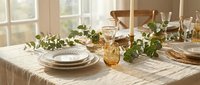 Elegant dining table setting with eucalyptus garland, amber glassware and neutral linens in warm natural light for entertaining and home decor.