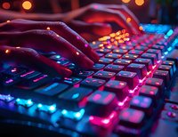 Hands typing on illuminated gaming keyboard with colorful RGB lighting effects in dark environment for esports and computer gaming content.