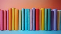 Row of colorful hardcover books arranged in rainbow spectrum order standing upright against coral background, creating vibrant minimalist composition for education themes.