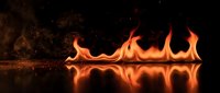 Dramatic orange flames dancing on reflective black surface creating mirror effect with sparks and embers in dark atmospheric background for design projects.