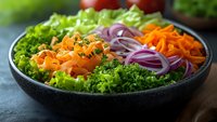 Fresh colorful vegetable salad bowl with lettuce, carrots, red onions and herbs for healthy eating and nutrition concepts.