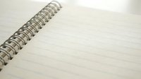 Open spiral-bound notebook with blank lined pages and metal wire binding, close-up view for writing, journaling, note-taking and office supplies concepts.