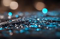 Glowing blue bokeh lights on dark background with scattered sparkles and water droplets creating magical atmospheric effect. Abstract macro photography.