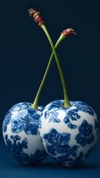 Artistic cherries decorated with blue and white porcelain floral pattern against dark background. Creative food styling concept for luxury dining and decor.