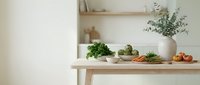 Modern kitchen counter with fresh vegetables and herbs arranged for healthy cooking and meal preparation in minimalist Scandinavian style interior.