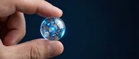 Hand holding transparent globe sphere with blue digital world map and network connections against dark background, representing global business, technology, and international communication.