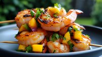 Grilled shrimp skewers with fresh mango salsa and herbs on black plate, close up view of juicy seafood appetizer garnished with cilantro and red onion.