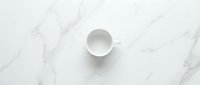 Empty white ceramic cup on marble surface, minimalist flat lay composition for beverage, kitchen, and lifestyle design projects.