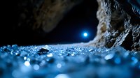 Mystical blue moonlight illuminates frost crystals on rocky surface creating magical winter atmosphere with bokeh effect and natural lens flare.