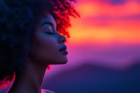 Young African American woman with natural curly hair in profile against vibrant sunset sky with purple and orange gradient colors creating dramatic silhouette effect.