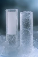 Frozen cylindrical ice formations rising from frosty surface against blurred winter background, showcasing natural crystallization patterns and frost textures.