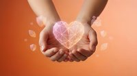 Two hands holding a glowing geometric heart shape against warm orange background, symbolizing love, care, charity, and compassion for healthcare and wellness concepts.